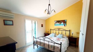 Ein Schlafzimmer mit Bett, Nachttisch, Lampe, Bilderrahmen und Deckenleuchte.