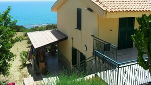 Ein zweistöckiges Haus mit Ziegeldach, einem Balkon mit Metallgeländer und Blick aufs Meer.