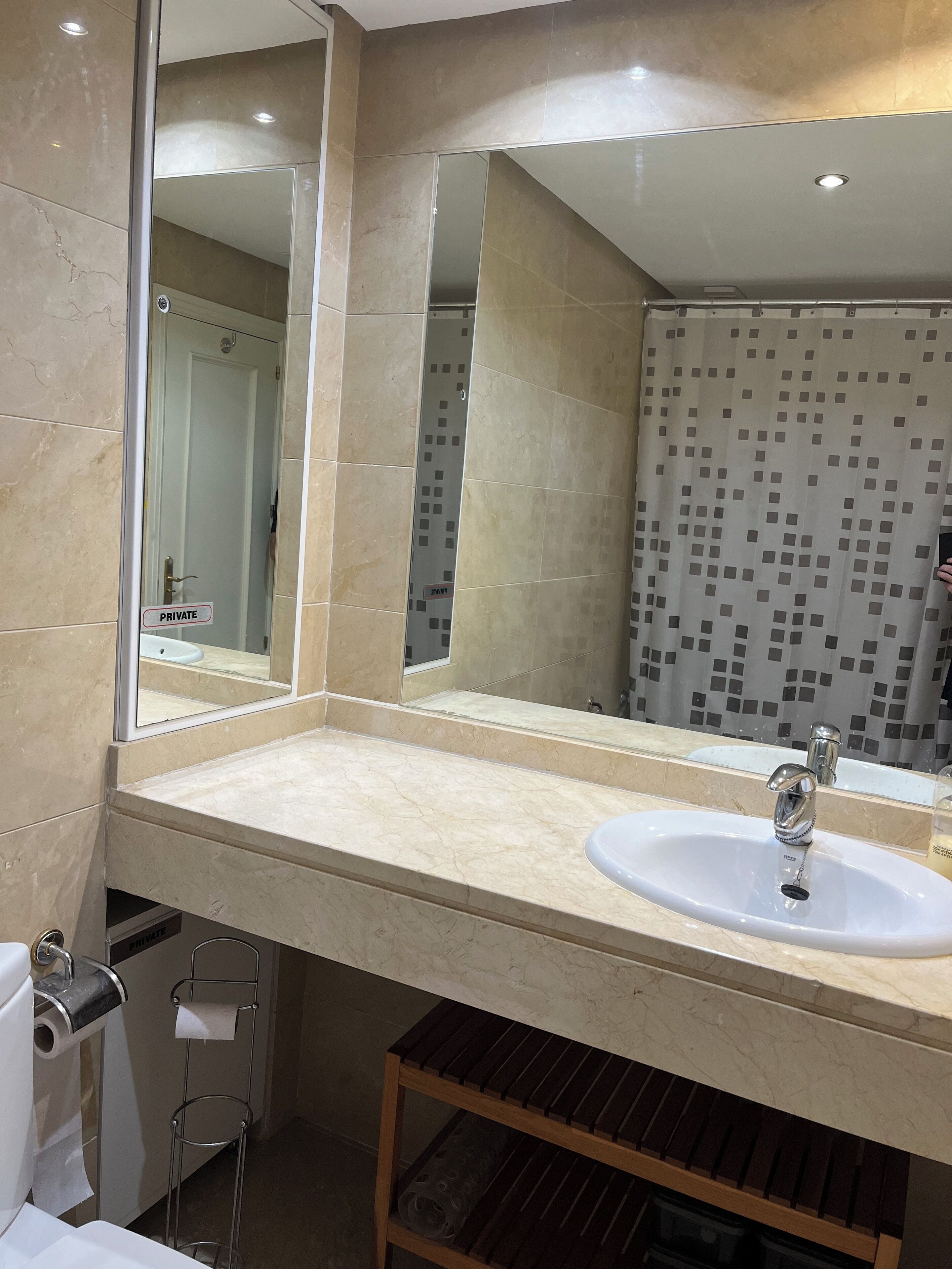 A modern bathroom with a large mirror, a sink, and a toilet.