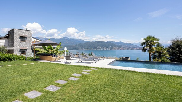 A modern house with a swimming pool, a patio with lounge chairs, and a view of a lake and mountains. - Relaxing Oasis: Villa with Private Pool & View (Baveno)