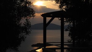 Une pergola en bois surplombant un plan d’eau paisible, avec une montagne visible au loin.