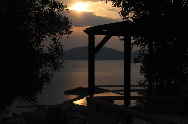 A wooden pergola overlooking a calm body of water with a distant mountain.