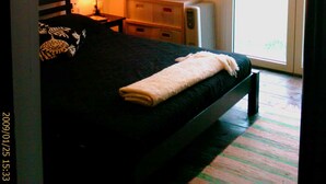 Une chambre à coucher avec un lit, une table de chevet, une lampe, une commode et une fenêtre.