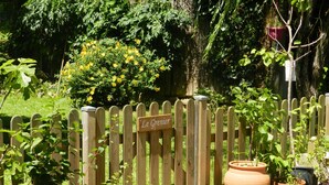 Une clôture en bois avec une pancarte indiquant « Le Grenier » et plusieurs plantes en pot.