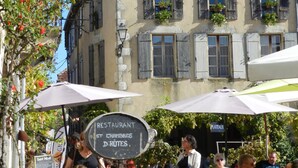 A building with a sign reading "Auberge Au Bastignac Chambres d'hotes Épicerie fine" and outdoor seating with umbrellas. - Gîte with pool, grounds, air-conditioning for peaceful family holidays in Landes (Sainte-Colombe)