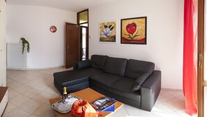 A living room with a sectional sofa, a coffee table with a bottle, glasses, and a book, and two paintings on the wall. - COLOR WITH PANORAMA AND RENOVATED PARKING (Careno)
