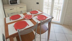 A dining area with a table set for four, a microwave, and a view of the outside balcony. - COLOR WITH PANORAMA AND RENOVATED PARKING (Careno)