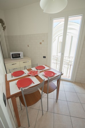 A dining area with a table set for four, a microwave, and a view of the outside balcony.