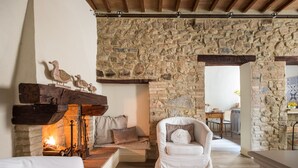 A rustic room with a stone wall, a fireplace, a white sofa, and a wooden bench.