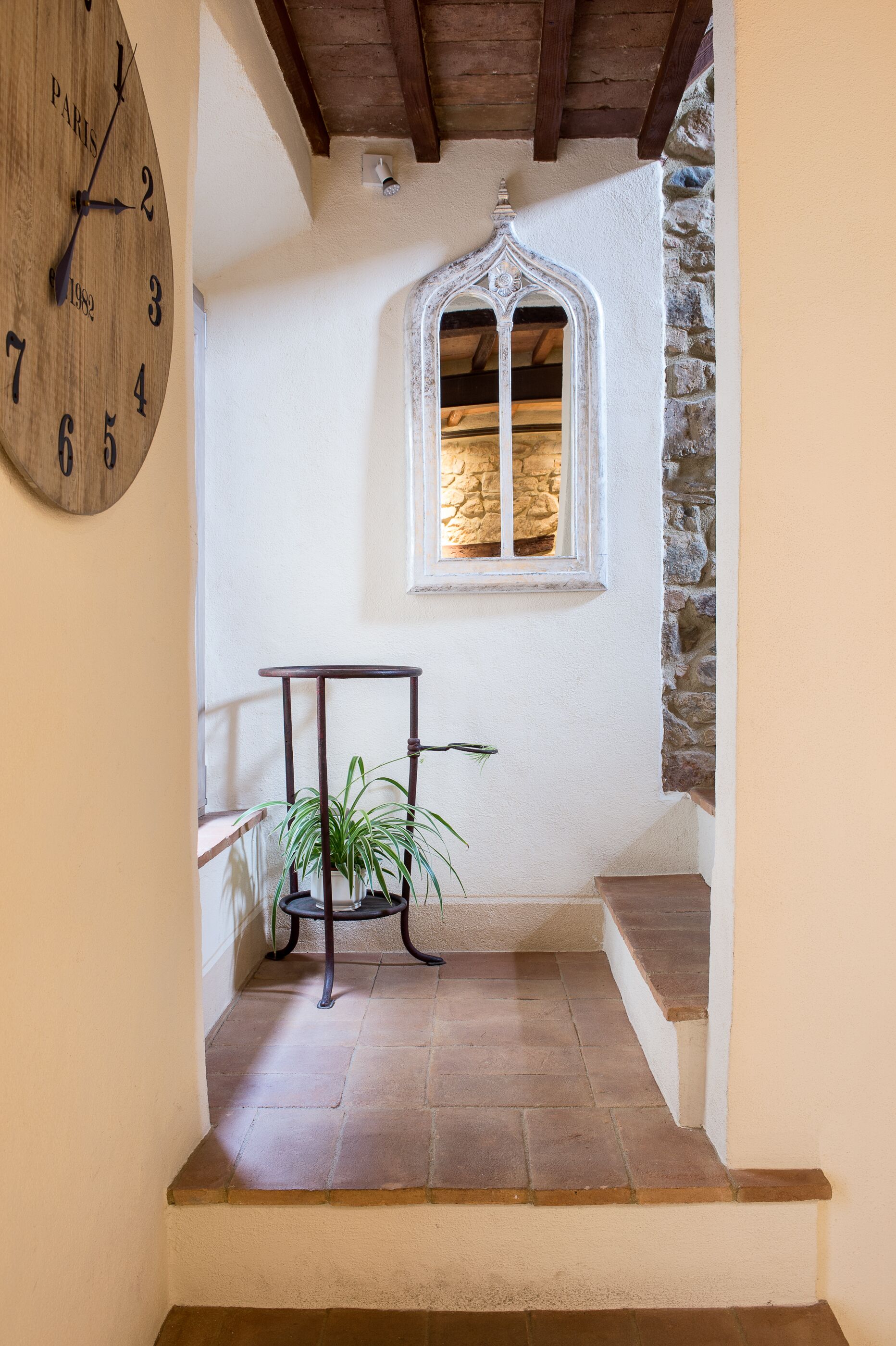 A staircase with a wooden floor, a potted plant, and a wall-mounted clock.