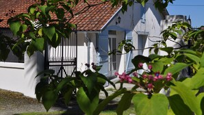 A white building with a red-tiled roof, a black gate, and a clear blue sky.