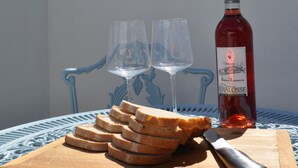 A table with a bottle of wine, two glasses, and a wooden board with slices of bread.