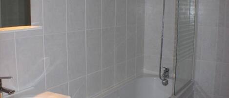 A modern bathroom with a white bathtub, a wooden vanity with a sink, and a glass-enclosed shower area.