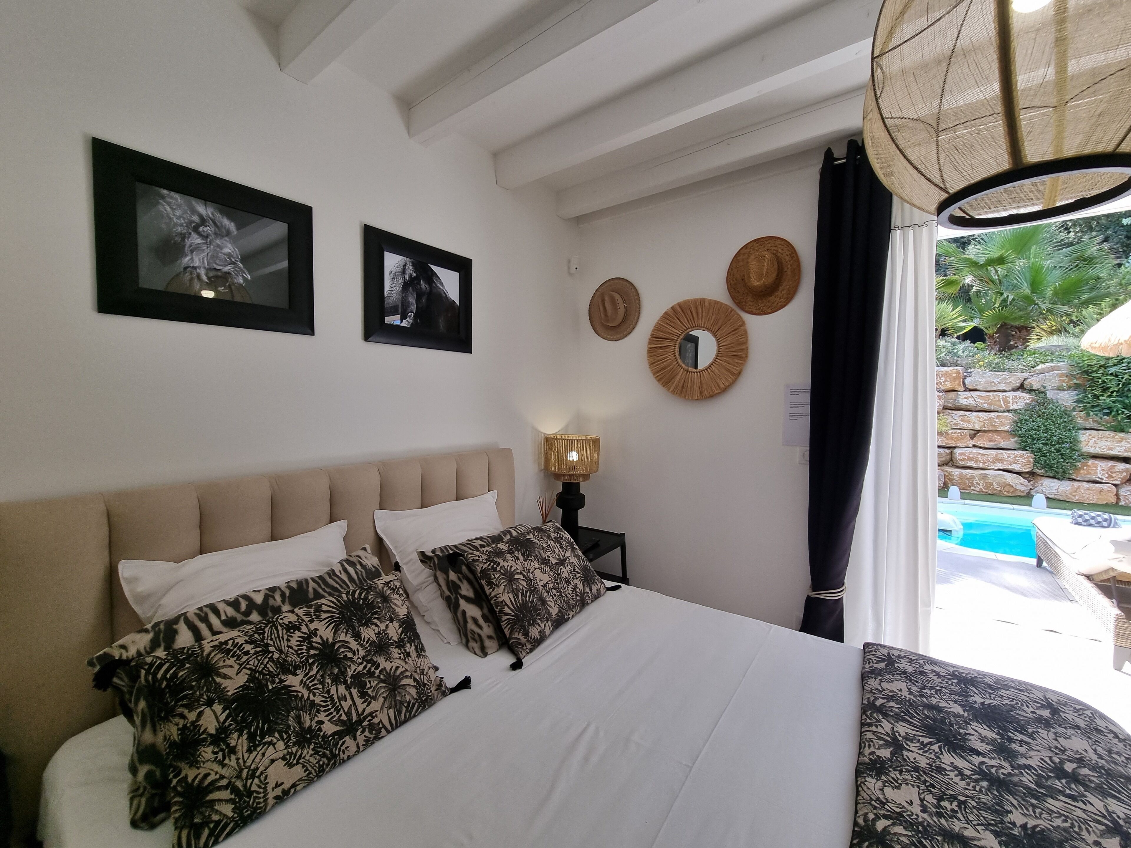 Une chambre à coucher avec un lit, deux tableaux encadrés, un miroir et une lampe.