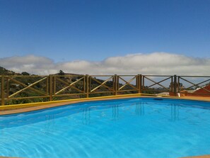Una piscina con cerramiento de madera y vistas a un paisaje montañoso.