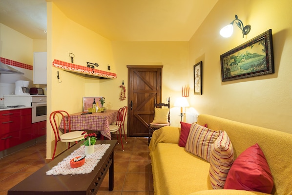 A compact living space with a dining area, a sofa, and a kitchen. - charming house in the middle of nature with pool .Ideal couples. (Moya)