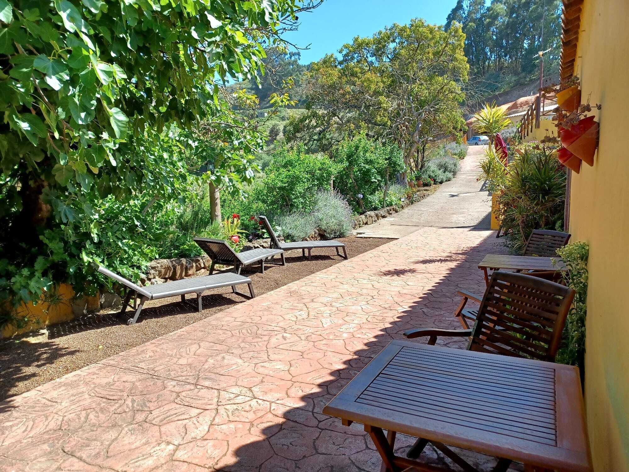 A patio with stone flooring, outdoor furniture, and lush greenery.