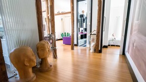 Un couloir doté d’un plancher en bois, d’une chaise violette et d’un buste sculpté de couleur blanche.