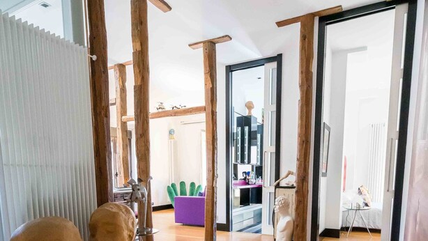 Une pièce spacieuse dotée d’un plancher en bois, d’une grande fenêtre et d’une porte donnant sur une autre pièce.