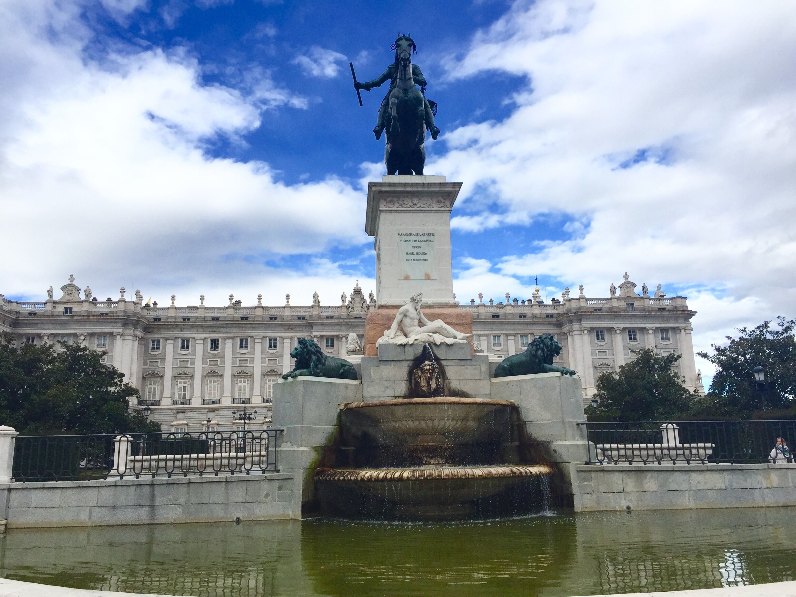 A fountain with statues in front of a large building with classical architecture.