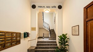 A staircase with a checkered floor, a wooden handrail, and a sign above reading 'PARVA, SEED APTH'.