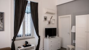 A modern, well-lit room with a white dresser, a television, and a small table.