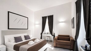 A modern hotel room with a bed, a desk, a chair, and a television.