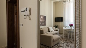 A hallway with a large mirror, a telephone, and a door leading to another room. - Alighieri Theatre charming suite (Ravenna)