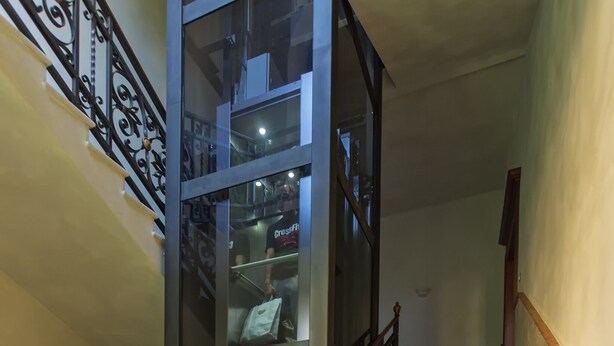 A staircase with ornate metal railings and a glass enclosure on one side. - Alighieri Theatre charming suite (Ravenna)