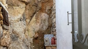 A narrow stone corridor with a rustic stone wall on one side and a white door on the other.