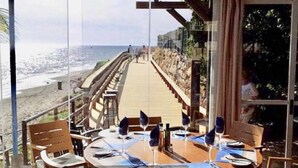 Un restaurante con vista a la playa y una terraza de madera.
