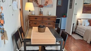 Een eetruimte met een houten tafel, stoelen, een vloerkleed en een decoratieve vaas.