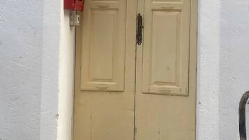 A double door with a number '30' sign above it, a red fire alarm box, and a patterned planter at the entrance.