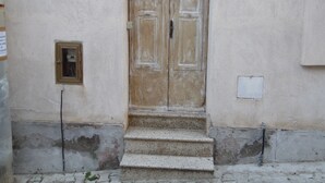 A weathered wooden door with a small window above it, a number '30' sign above the door, and a utility box to the right.
