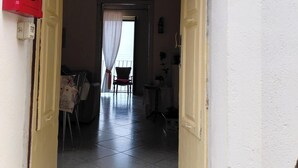 A doorway leading to a room with a chair, a table, and a small table with a vase.