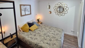 Ein Schlafzimmer mit Bett, Nachttisch, Wandspiegel und einem gerahmten Bild.