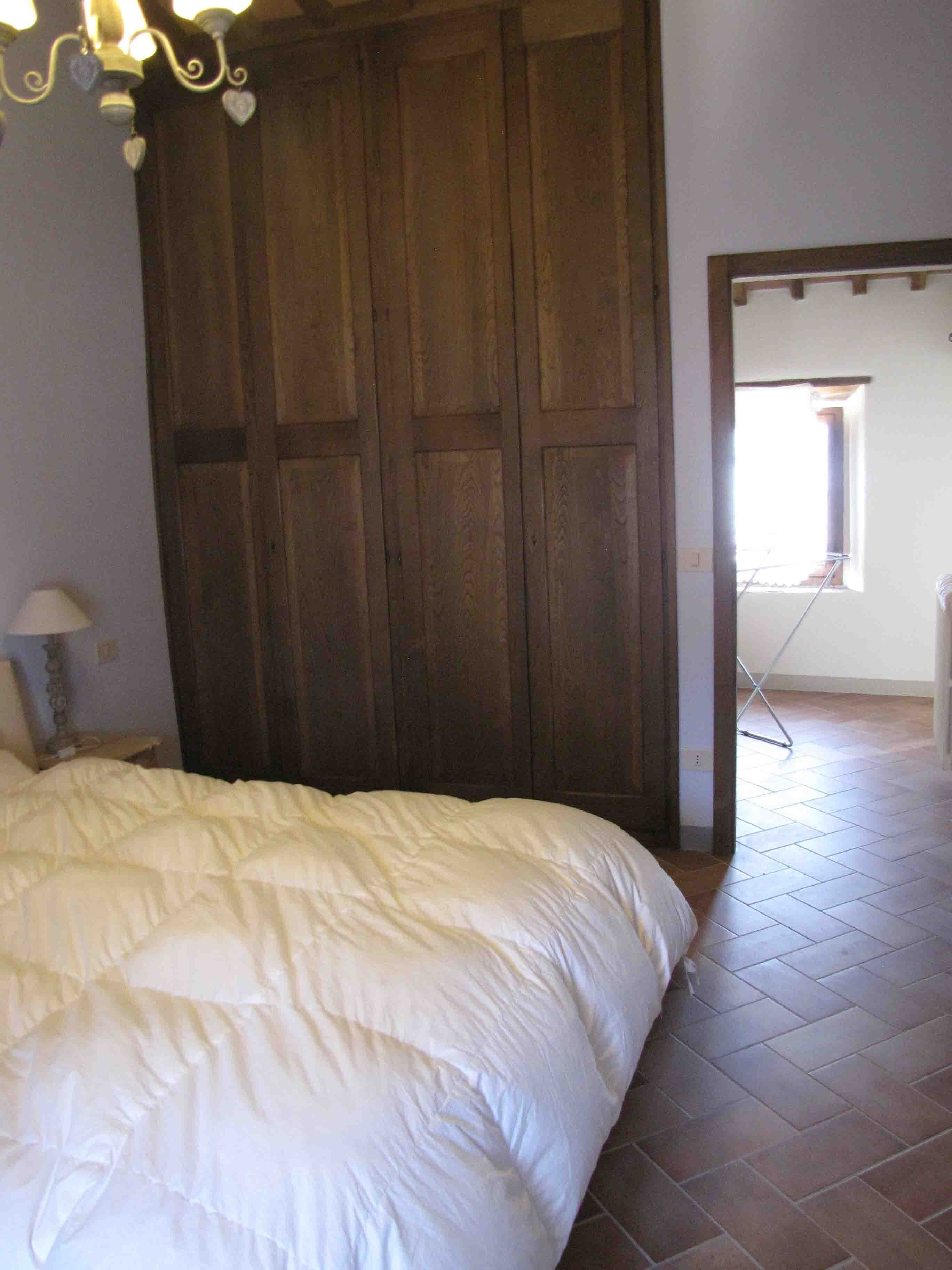 Ein Schlafzimmer mit einem großen Bett, einem Holzschrank und einem Fenster mit Blick.