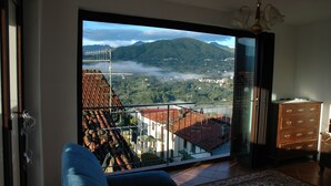 Ein Zimmer mit einer großen Schiebeglastür, die auf einen Balkon mit Blick auf eine Berglandschaft führt.