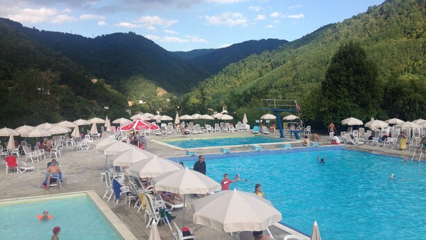 Ein Poolbereich mit mehreren Schwimmbecken, Liegestühlen und Sonnenschirmen.