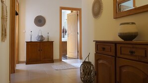 Un couloir avec des armoires en bois, un panier en osier et un miroir accroché au mur.