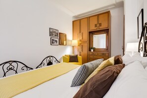 Una habitación de hotel con una cama, una silla amarilla, un armario de madera y un espejo.