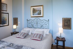 Una cama bien hecha con un cabecero decorativo, dos lámparas de noche y cuadros en las paredes.