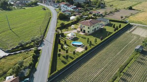 Vista aerea di una zona residenziale con una casa grande, una piscina e giardini curati.