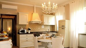 Una cucina con mobili bianchi, un lampadario e un tavolo da pranzo per quattro persone.