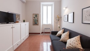 Un salon avec un canapé, un téléviseur et des œuvres d’art accrochées aux murs.