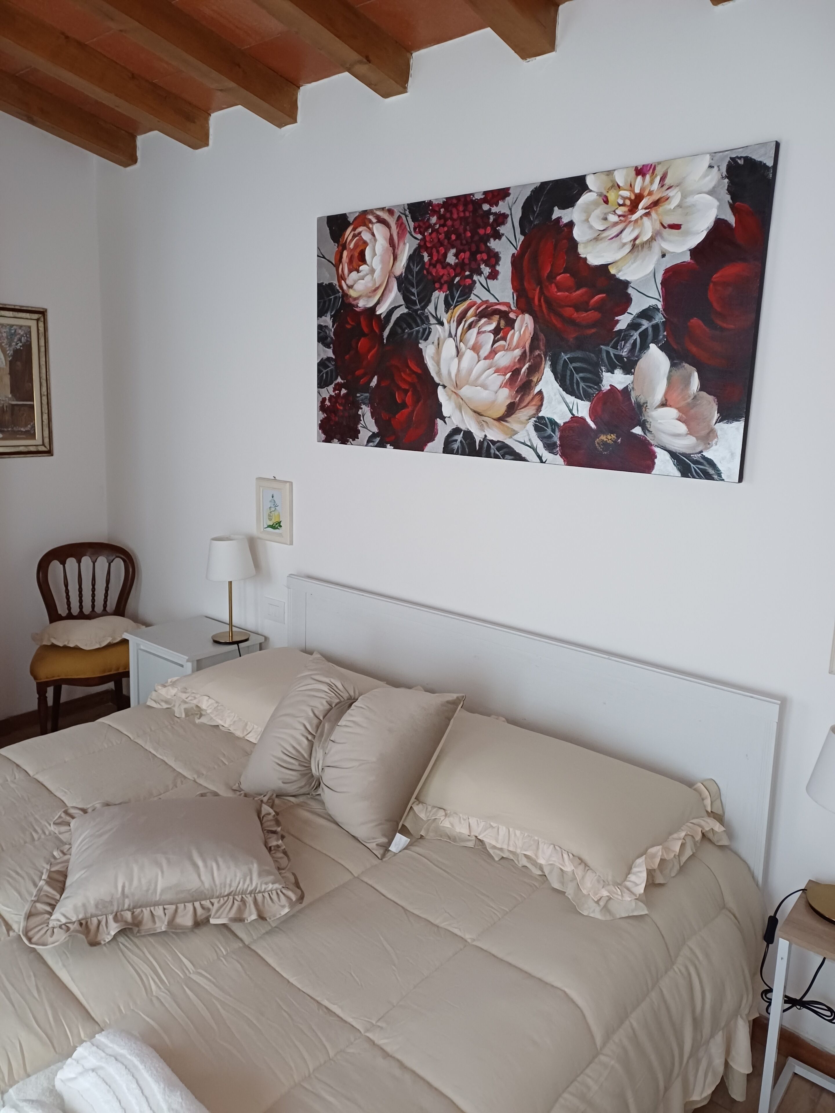 Ein Schlafzimmer mit einem großen Bett, einem Nachttisch, einem Sessel und einem Wandbild.