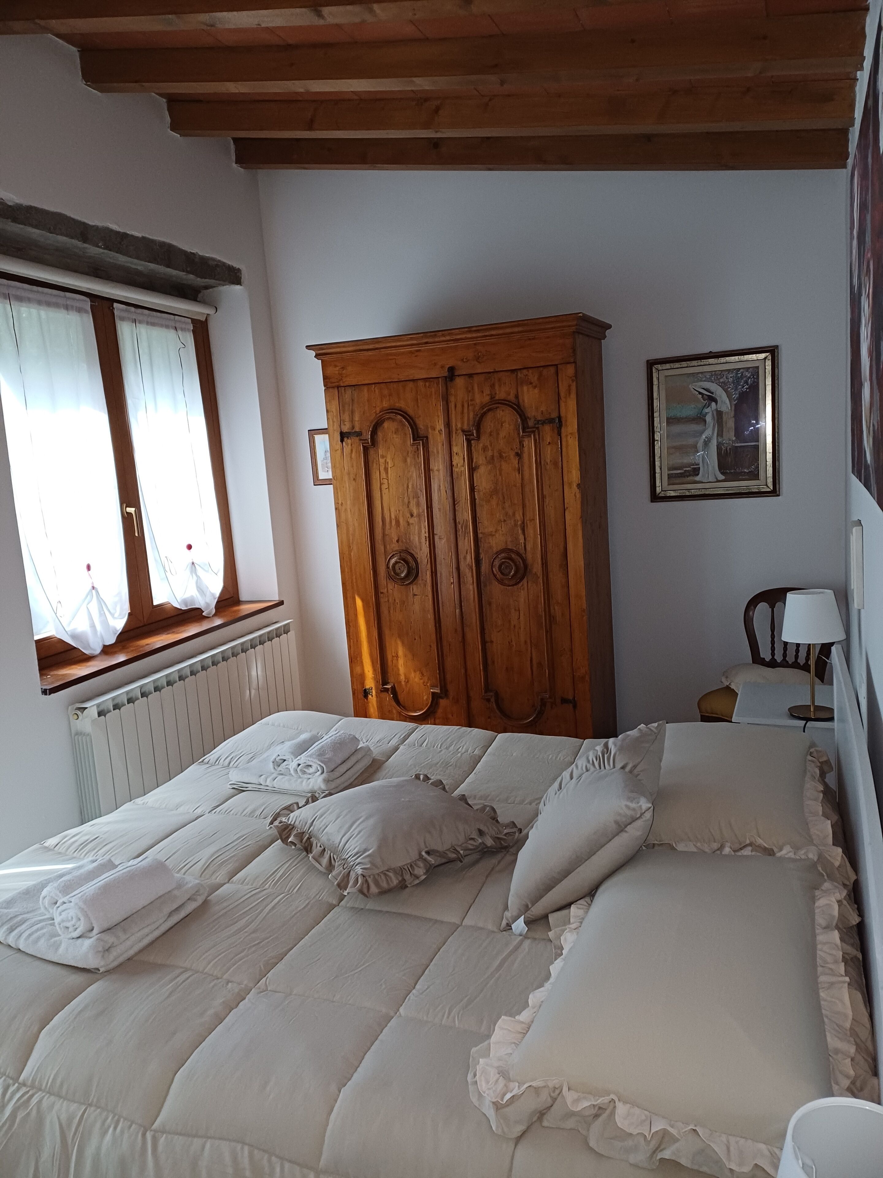 Une chambre à coucher avec un grand lit, une armoire en bois et une fenêtre avec des rideaux.