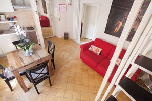 A compact living space with a dining area, a red sofa, and a kitchen.