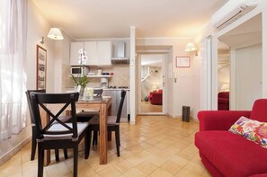 A compact living space with a dining area, kitchen, and a red sofa.