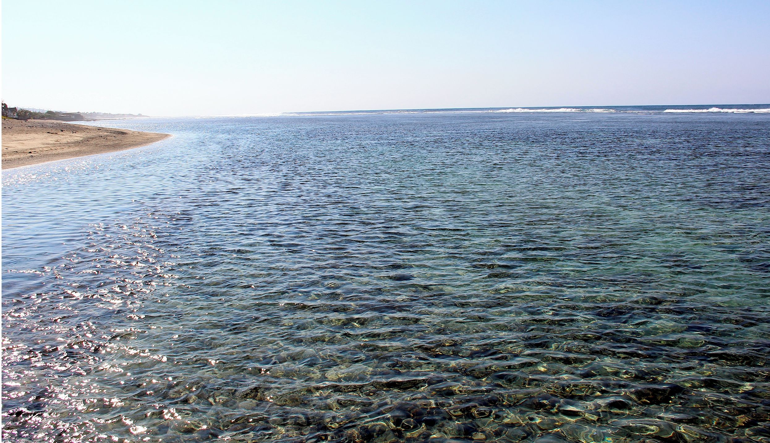 Ein freier Blick auf einen Strand mit ruhigem Wasser und einer entfernten Küste.